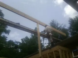 Carpenter setting a ridge beam over a new addition frame — Ice Dam Removal by Roofing Brothers in Faxon