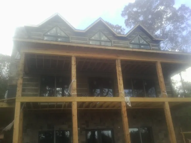 Dormers and porch framing on a large log home under construction — Roof Coating work by our crew in Faxon
