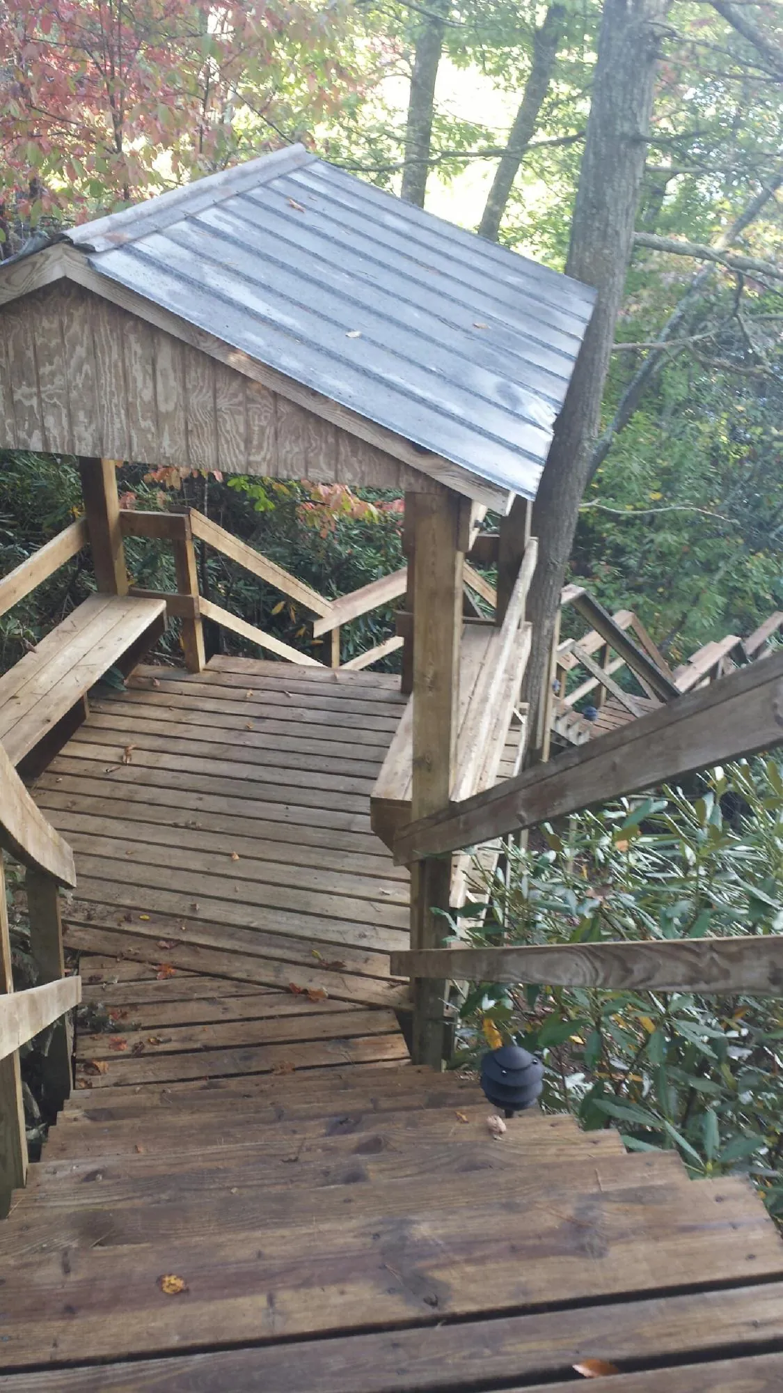 Metal roofed shelter over wooden steps on a wooded walkway — Skylight Repair & Installation work by our crew in Faxon