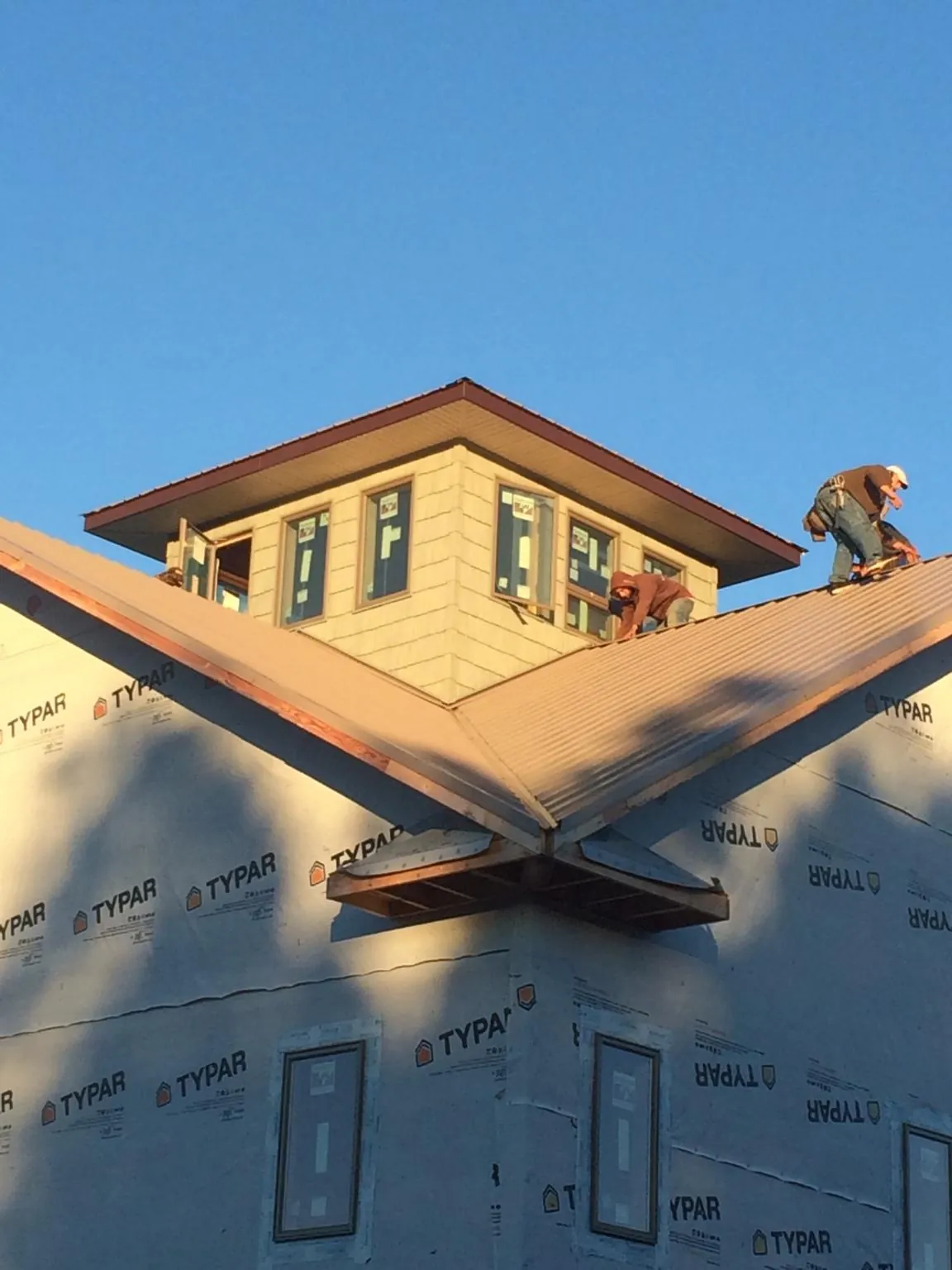 Roofers working around a rooftop cupola on a new metal roof at sunset — Roof Waterproofing in Faxon by Roofing Brothers